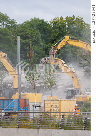 Close-up view of crumbling bridge structure demolition in Magdeburg Damaschkeplatz  exposed steel rebar falling concrete chunks. Rubble piles and demolition machinery emphasize destruction progress 127428941