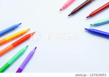 A collection of colorful felt-tip pens arranged in a circular pattern around a blank white center 127428953