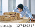 建築模型を見て建物の条件や予算を分析しプランニングをする1人の男性 建築模型を見て建物の条件や予算を分析しプランニングをする1人の男性 127429217