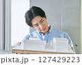 大学の工学部の建築学科で建物の設計を模型を見て勉強する笑顔の男性の大学生 大学の工学部の建築学科で建物の設計を模型を見て勉強する笑顔の男性の大学生 127429223