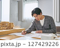 建築の模型を横に都市計画の為の設計図を書く工学部の大学の建築学科で勉強する大学生の男性 建築の模型を横に都市計画の為の設計図を書く工学部の大学の建築学科で勉強する大学生の男性 127429226