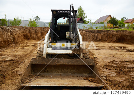 Excavator in the excavation at the construction site during the day 127429490