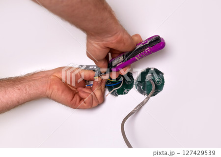 Home renovation project shows hands working on electrical wiring in a wall cavity at a residential location 127429539