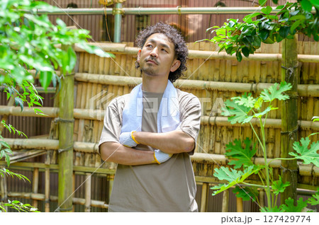 庭園内の竹垣を前に腕を組んで考え込む男性が作業計画を練る静かな夏のワンシーン 庭園内の竹垣を前に腕を組んで考え込む男性が作業計画を練る静かな夏のワンシーン 127429774