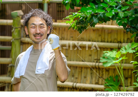 作業終わりの男性が拳を上げながらほほ笑む達成感に満ちた明るい夏の庭園ポートレート 127429792