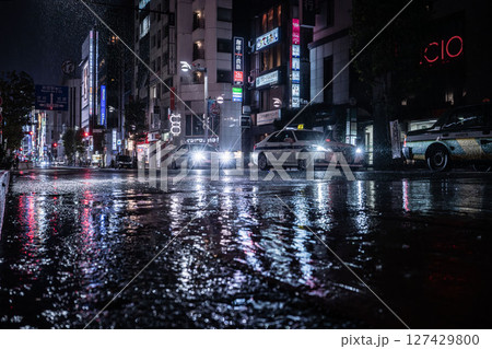雨の新宿三丁目、水たまりに映る繁華街、薄暗い路地裏 雨の新宿三丁目、水たまりに映る繁華街、薄暗い路地裏 127429800