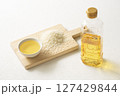 木のボードに乗せた米油と米とペットボトル 127429844