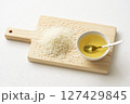木のボードに乗せた米油と米とスプーン 127429845