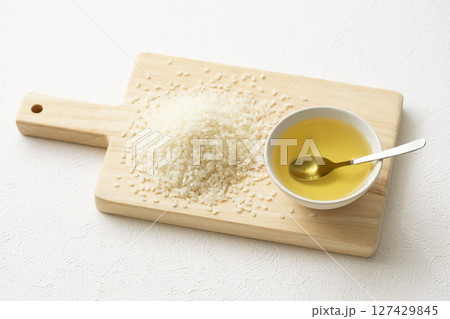 木のボードに乗せた米油と米とスプーン 木のボードに乗せた米油と米とスプーン 127429845