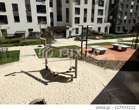 Modern courtyard playground with wooden swing and balance elements encourages children's physical activity, motor skills development and outdoor fun in a safe, clean urban environment Modern courtyard playground with wooden swing and balance elements encourages children's physical activity, motor skills development and outdoor fun in a safe, clean urban environment 127433212