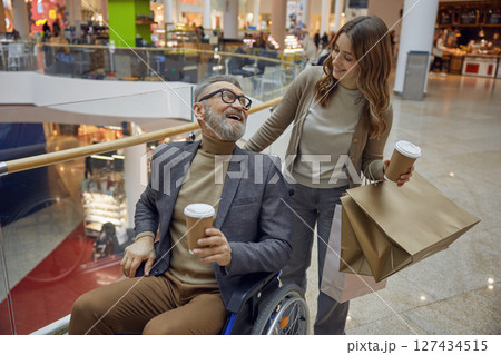 A joyful mall outing with a wheelchair user and companion, highlighting their fun experience 127434515