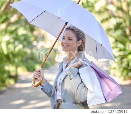 Sun, umbrella and woman with bags from shopping with smile and happy walking in park. Summer, nature and girl with shopping bags from luxury designer boutique and protection from uv rays in sunshine. Sun, umbrella and woman with bags from shopping with smile and happy walking in park. Summer, nature and girl with shopping bags from luxury designer boutique and protection from uv rays in sunshine. 127435912