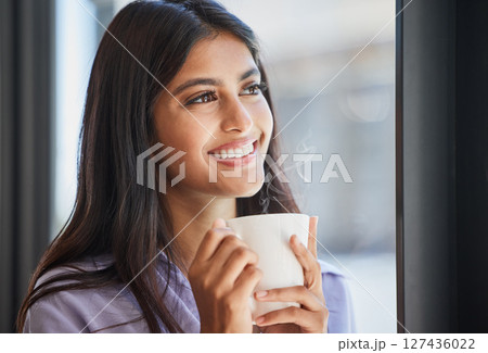 Happy, woman and coffee at a window for relax, thinking and daydream about future, goal and ideas in her home. Face, tea and indian girl smile in her living room, enjoy calm drink and window view Happy, woman and coffee at a window for relax, thinking and daydream about future, goal and ideas in her home. Face, tea and indian girl smile in her living room, enjoy calm drink and window view 127436022