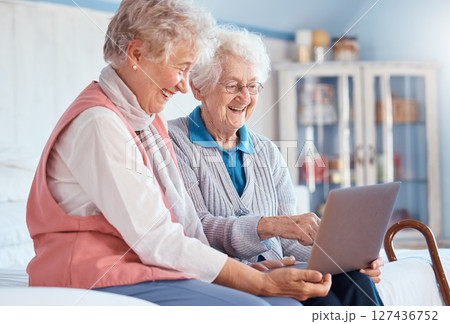 Senior women, friends and laptop in home for social media, watching movie or video call. Tech, computer and happy elderly retired females streaming video or internet browsing while talking together. Senior women, friends and laptop in home for social media, watching movie or video call. Tech, computer and happy elderly retired females streaming video or internet browsing while talking together. 127436752