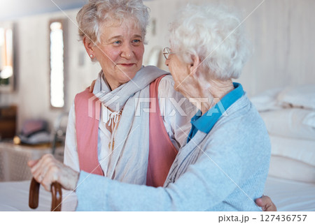 Happy, friends and senior women talking and bonding in a bedroom together of a retirement home. Happiness, conversation and retired elderly female best friends with a smile speaking of gossip in room 127436757