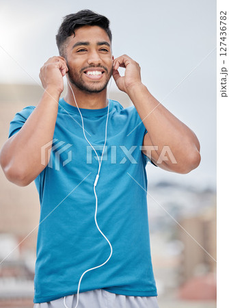 Man, music and earphones for city exercise for wellness, training and running by blurred background. Happy runner, listening and streaming on internet, web or app to relax at workout in urban metro 127436782