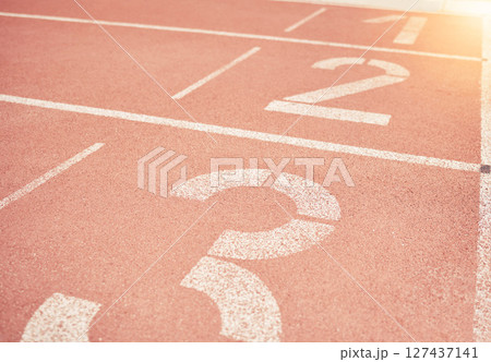 Sports, athletics and number on race track in stadium for training, sprint and running start position. Texture, ground and running track with nobody for fitness, exercise and workout for sport event Sports, athletics and number on race track in stadium for training, sprint and running start position. Texture, ground and running track with nobody for fitness, exercise and workout for sport event 127437141