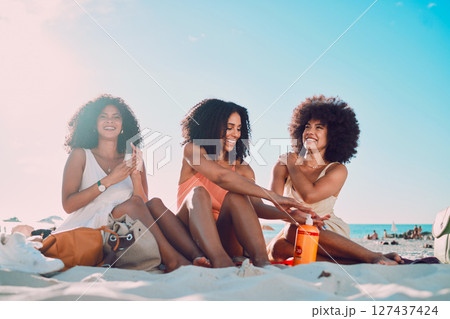 Friends, sunscreen and relax at beach, happy and summer holiday, travel and blue sky in Miami, happy and smile. Blaxk women, vacation and ocean vacation, happiness and afro with skincare and safety 127437424