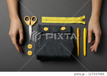 Handmade denim bag, materials, tools and hands on gray background, top view 127437466