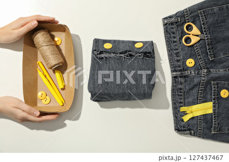Handmade denim bag, materials, tools and hands on white background, top view Handmade denim bag, materials, tools and hands on white background, top view 127437467
