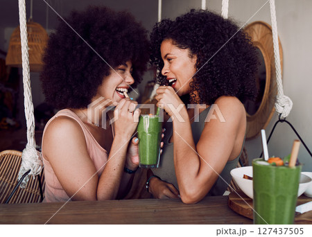 Friends, woman and drinking smoothie together in cafe, restaurant or date with comic laugh at table. Black women, share or smile with healthy juice, drink or health cocktail for love, bonding or care 127437505