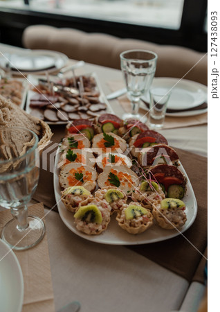 Festive table setting with abundant charcuterie, appetizers, and glassware in a neutral-toned dining room, capturing a celebratory moment. Festive table setting with abundant charcuterie, appetizers, and glassware in a neutral-toned dining room, capturing a celebratory moment. 127438093