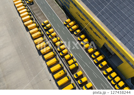 Delivery vans hub with solar panel on a roof. Fleet of yellow post vehicles. 127438244