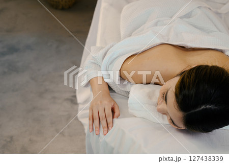 Serene moment in a wellness spa as woman prepares for a rejuvenating body massage 127438339
