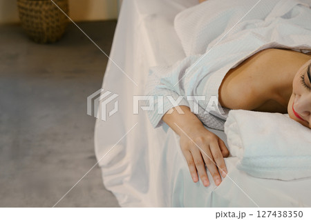 Top view of woman relaxing on a spa bed in white robe, ready for a massage treatment. Wellness concept Top view of woman relaxing on a spa bed in white robe, ready for a massage treatment. Wellness concept 127438350