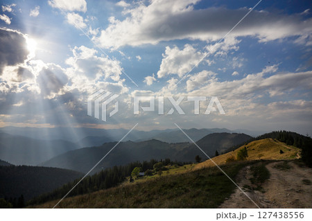 Beautiful mountain landscape with dramatic clouds and sunlight breaking through in a serene setting during early evening Beautiful mountain landscape with dramatic clouds and sunlight breaking through in a serene setting during early evening 127438556