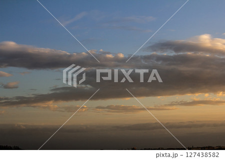 Colorful clouds drift across a serene sky at dusk over a peaceful landscape in the evening Colorful clouds drift across a serene sky at dusk over a peaceful landscape in the evening 127438582