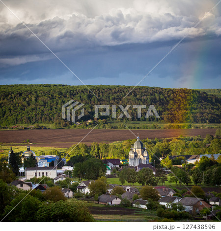 Cloudy landscape with hills villages and a church under dramatic skies during late afternoon in a rural area 127438596