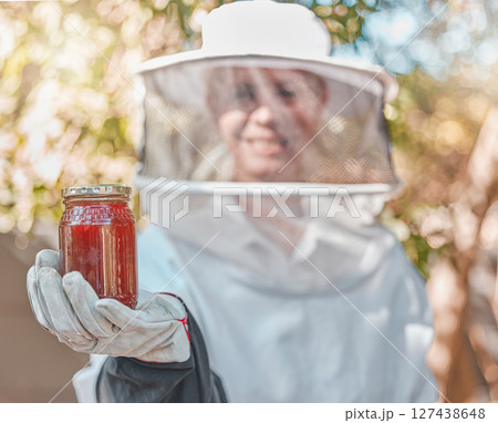 Hand, honey and jar with a woman beekeeper working in the countryside in the production of a natural product. Farm, agriculture and sustainability with a female farmer holding a honeyjar outdoor Hand, honey and jar with a woman beekeeper working in the countryside in the production of a natural product. Farm, agriculture and sustainability with a female farmer holding a honeyjar outdoor 127438648