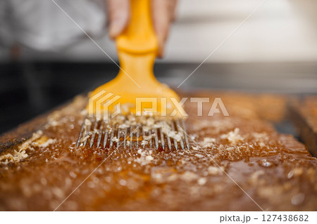 Beekeeping, honey frame and production for sustainable farming with scraping tool and frame for honeycomb, beeswax and food industry. Hands of bee farmer or apiarist working with natural product 127438682
