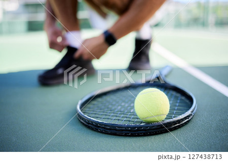 Tennis ball, racket and man tie shoes on tennis court preparing for competition, game or match. Exercise, fitness and tennis player getting ready for practice, training or workout outdoors on field. 127438713