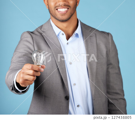 Lightbulb, knowledge and businessman with a creative idea, strategy and innovation on a blue studio background. Electricity, business and manager with a smile for solution, creativity and inspiration 127438805