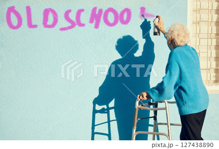 Senior woman, graffiti and wall with spray paint for street art in city, town or metro in retirement. Elderly rebel, painting or pop art in urban outdoor with vandalism, spray or painting in sunshine 127438890