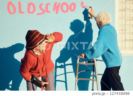 Senior women, friends and spray paint for humor, graffiti and street art on wall of nursing home building. Old people breaking the law with illegal activity outdoor Senior women, friends and spray paint for humor, graffiti and street art on wall of nursing home building. Old people breaking the law with illegal activity outdoor 127438896