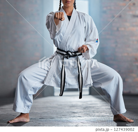 Karate, sports and fitness with a woman fighter or athlete training in a gym while wearing her gi uniform. Health, sport and workout with a female martial artist exercising in a dojo or health club Karate, sports and fitness with a woman fighter or athlete training in a gym while wearing her gi uniform. Health, sport and workout with a female martial artist exercising in a dojo or health club 127439002