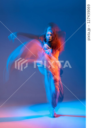 Jazz-funk dancer in a blur of blue and orange light, expressing movement and power in an artistic studio setting. 127439069