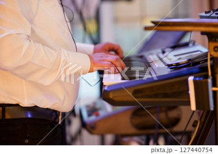 Live Music Performance Featuring a Keyboardist in a Formal Setting with musical Equipment, Stage Lighting, and White Shirt 127440754