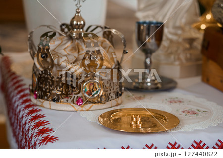 Eastern Orthodox Coronation Ceremony: Golden Crown, Chalice, and Paten on Red Textile Altar, Religious Ritual, Silverware, Sacred Objects 127440822