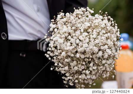 Wedding Bouquet of White Baby's Breath Held by a Groom in a Black Suit, Elegant Ceremony Floral Arrangement, Soft Romantic Style. 127440824