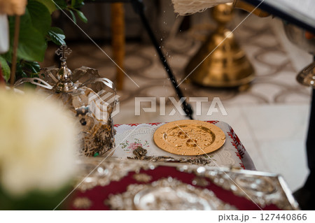 Eastern Orthodox Wedding Ceremony: Blessing of the Rings with Silverware and Floral Arrangement, Gold Disks, Red Textile Background 127440866