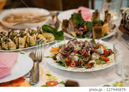 Lavish Mediterranean Feast on Table with Colorful Salads, Appetizers, and Drinks at Family Gathering in Warm Interior Setting. 127440876
