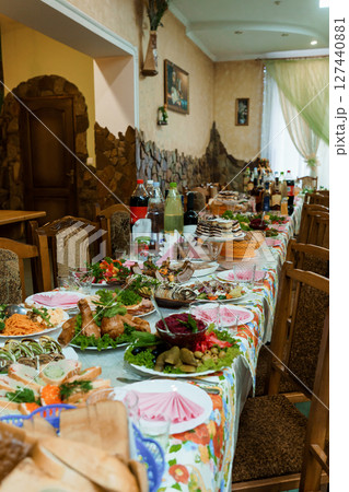 Abundant Georgian Feast Table Setting: Traditional Dishes, Wine, Festive Celebration, Rustic Interior, Warm Colors, Culinary Culture, Family Gathering. 127440881