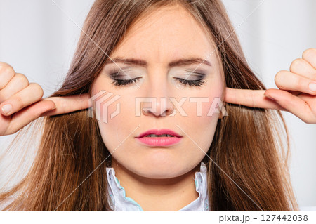 Stressed woman with closed eyes put fingers in ears, 127442038
