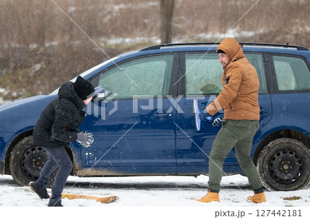 Father and son teamwork: clearing snow and ice from their car on a cold winter day. Preparing for a journey. Father and son teamwork: clearing snow and ice from their car on a cold winter day. Preparing for a journey. 127442181