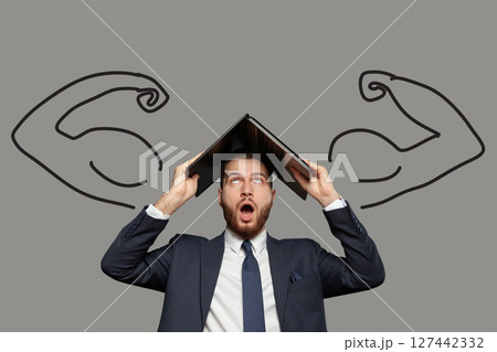 Emotional shocked businessman in suit with laptop on his head on grey background Emotional shocked businessman in suit with laptop on his head on grey background 127442332