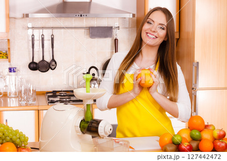Woman in kitchen preparing fruits for juicing Woman in kitchen preparing fruits for juicing 127442472